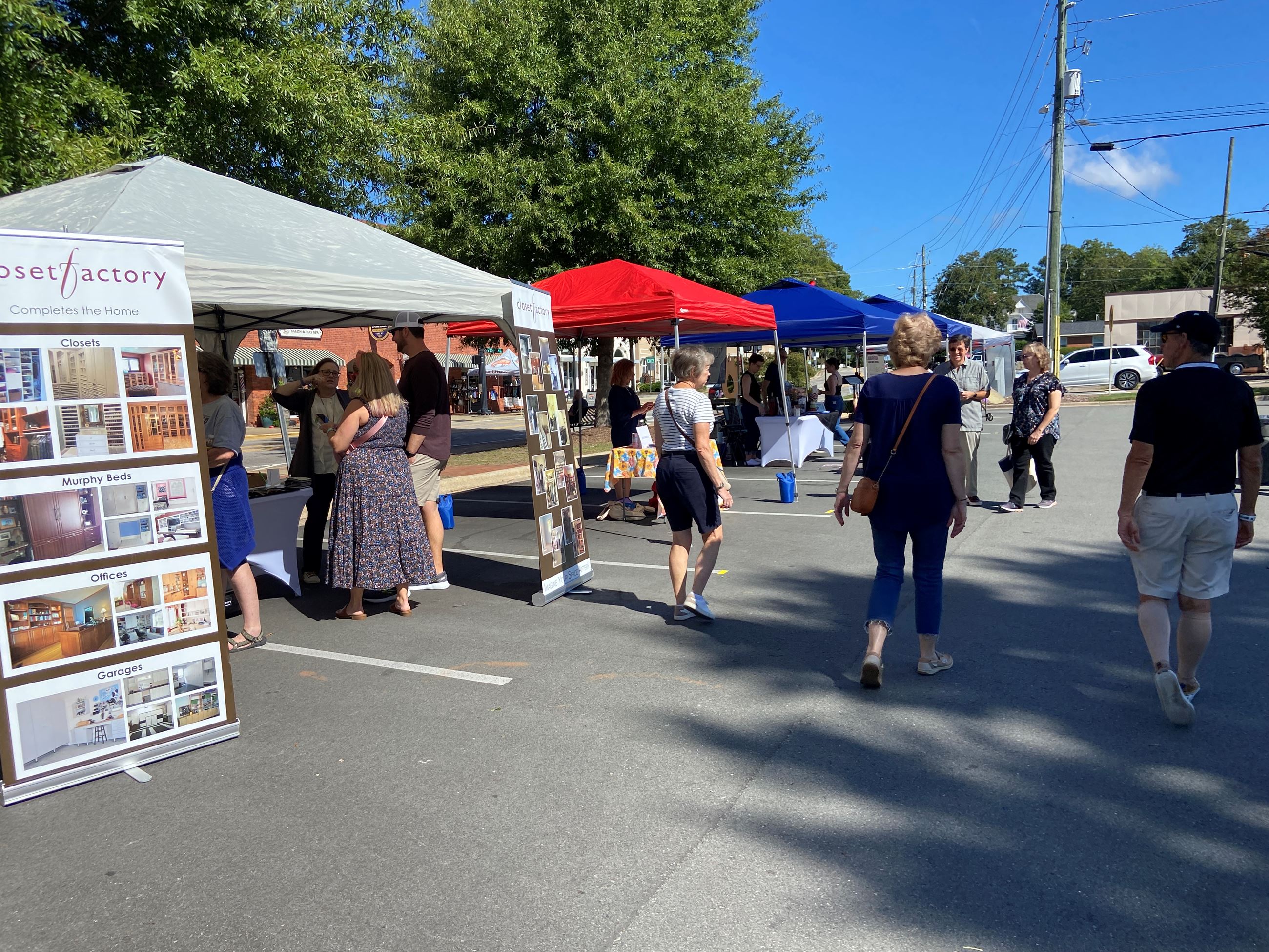 People walking around business tents in the Depot parking lot