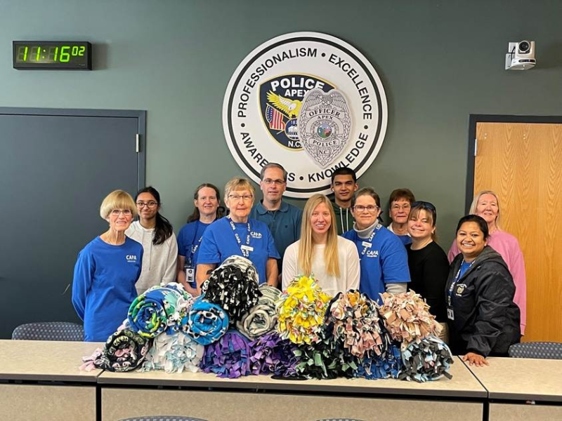 Image shoes a group of volunteers in front of fleece blankets on a table